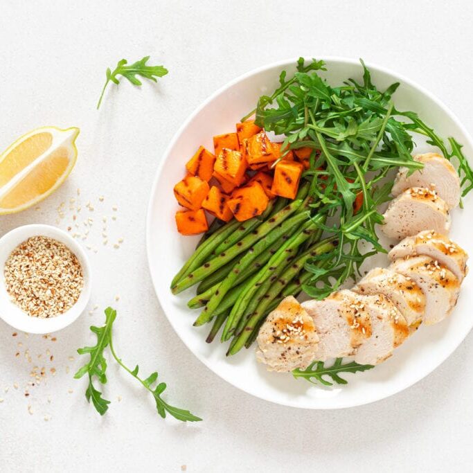 Grilled chicken breast, fillet with butternut squash or pumpkin, green beans and fresh arugula salad, healthy food, top view